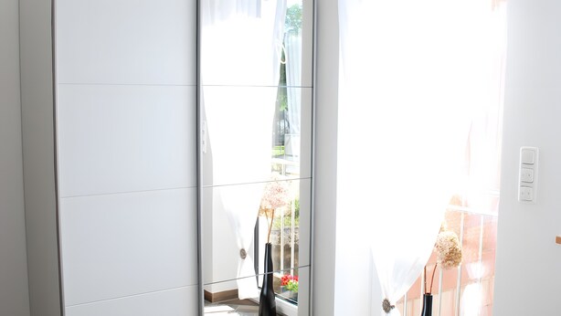 Un intérieur moderne avec une grande fenêtre, un vase rempli de fleurs et un interrupteur fixé au mur.