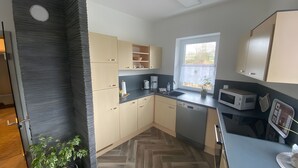 Une cuisine moderne avec un parquet disposé en chevrons, des appareils électroménagers intégrés et une fenêtre offrant une belle vue.