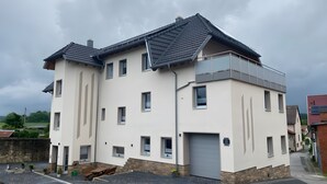Un immeuble résidentiel à plusieurs étages, doté d’un toit plat, de nombreuses fenêtres et d’une entrée sécurisée par un portail.