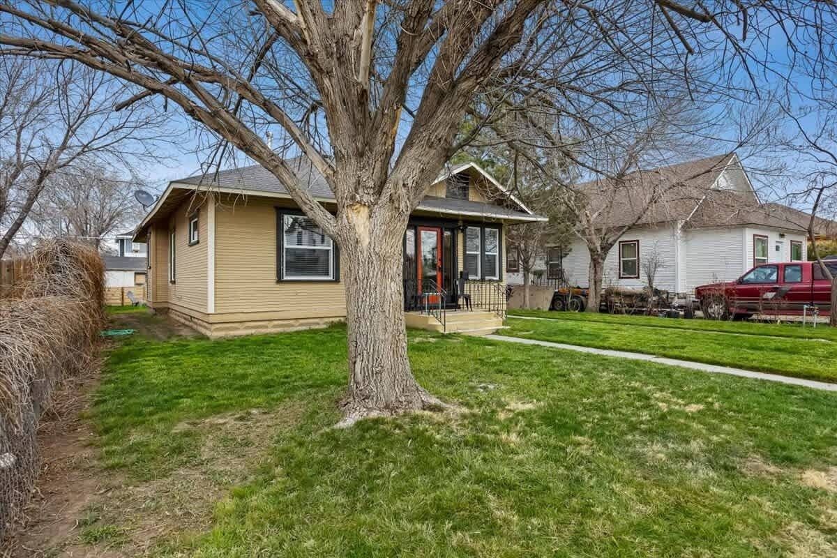 A single-story house with a front porch, a tree in front, and a red truck parked in the driveway.