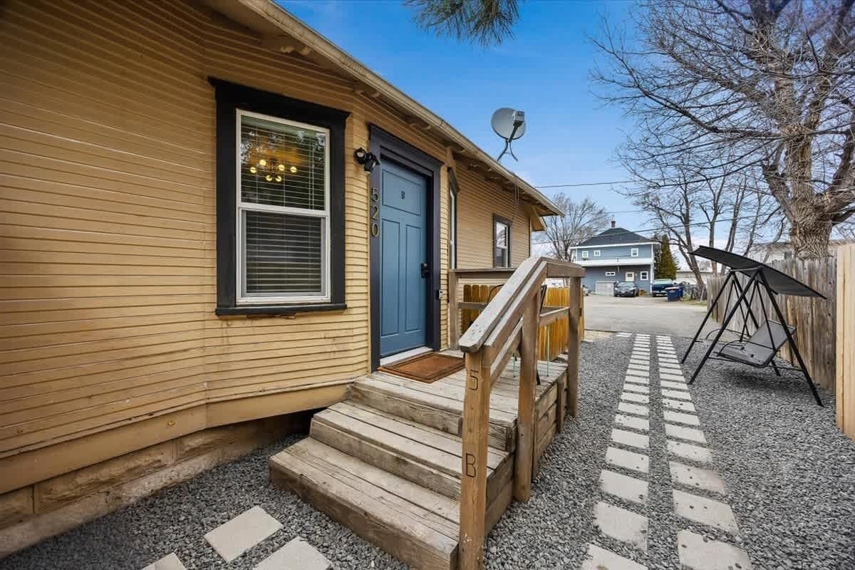 A wooden house with a blue door, a satellite dish, and a gravel driveway.