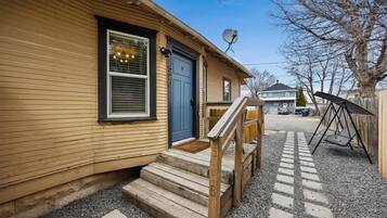 A wooden house with a blue door, a satellite dish, and a gravel driveway.