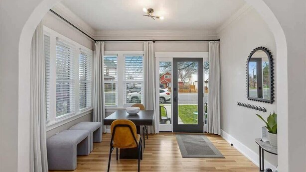 Un comedor con una mesa, un banco y sillas, una lámpara en el techo y vistas al exterior a través de un ventanal.
