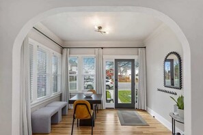 A dining area with a table, bench, and chairs, a ceiling light, and a view through a glass door to the outside. - #StayInMyDistrict TwinFalls Downtown Duplex (Twin Falls)