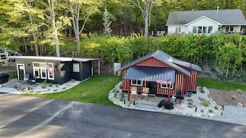 A cabin with a porch, a small deck, and an American flag.