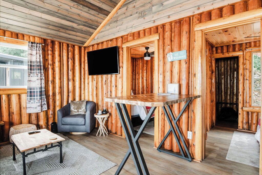 A log cabin interior with a sofa, a table, a TV, and a sign.