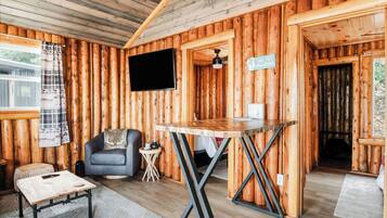 A log cabin interior with a sofa, a table, a TV, and a sign.