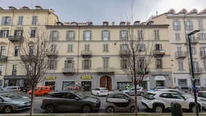 A street with parked cars, a building with 'MIX Markt' signs, and a 'PROVIDEDIA' sign. - The Green Attic by Wonderful Italy (Torino)