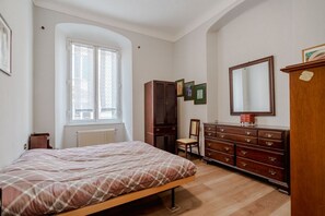 A bedroom with a bed, a dresser, a chair, a wardrobe, and a window. - GuestHost - Spacious and welcoming 120 square meters apartment, perfect for six people, located on the second floor of a historic building with an elevator (NOT accessible to disabled guests).The property is centrally located in Genoa, just a 5-minute wa (Genoa)