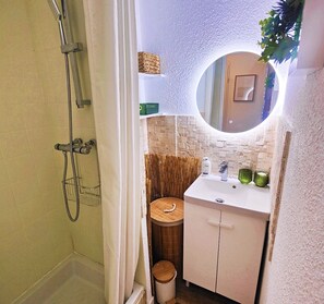 Ein Badezimmer mit Dusche, Waschbecken, Spiegel und Toilette.