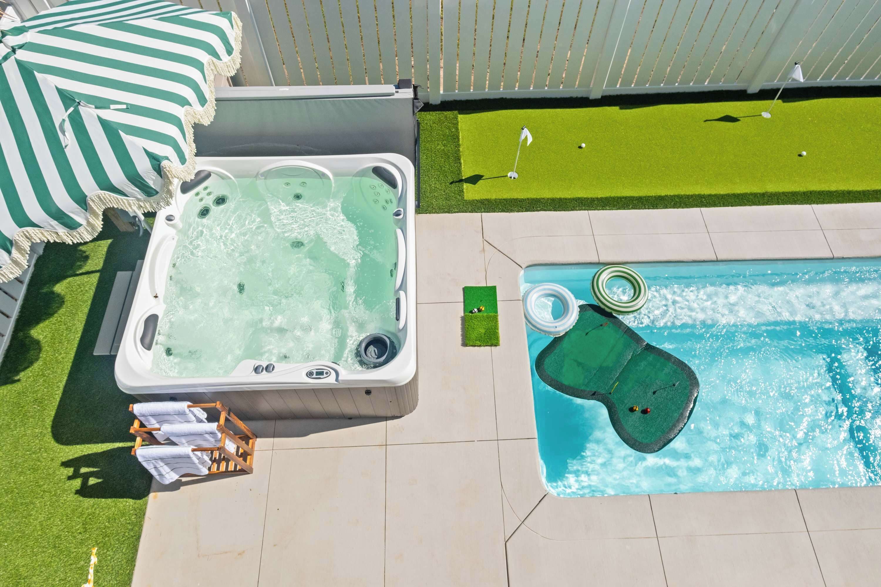 Una vasca idromassaggio, una piscina con un prendisole verde e un campo pratica da golf.