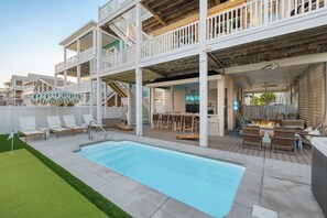 Uma área à beira da piscina, com piscina, assentos externos e um bar.