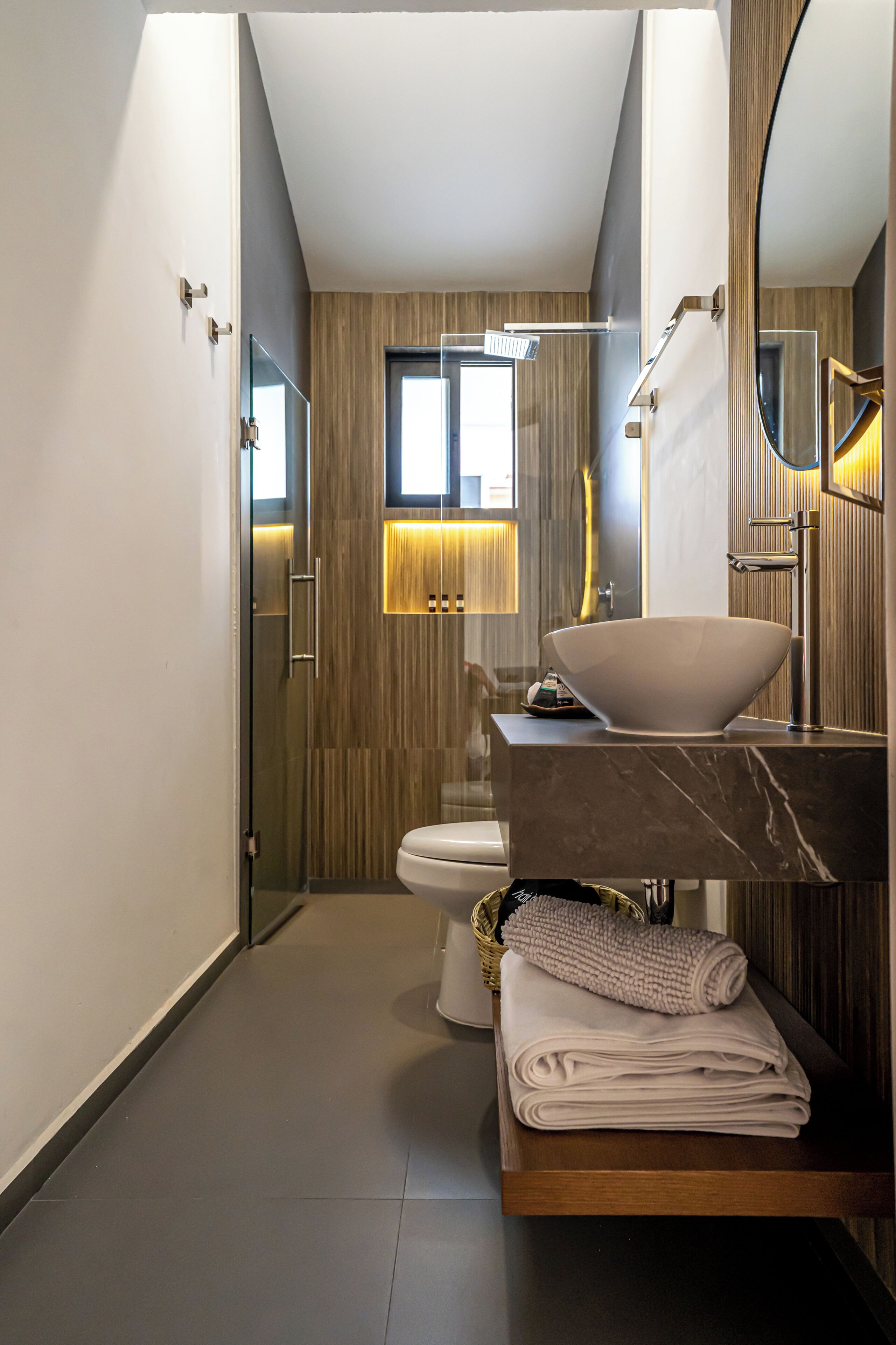 A modern bathroom with a glass shower enclosure, a marble sink, and a wooden vanity.