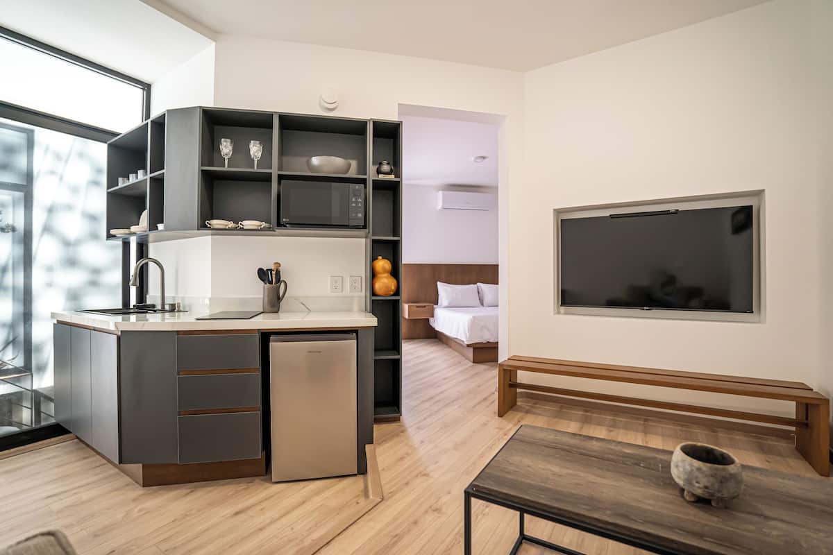 Una cocina moderna con lavavajillas integrado, un comedor con mesa de madera y un televisor de pantalla plana grande montado en la pared.