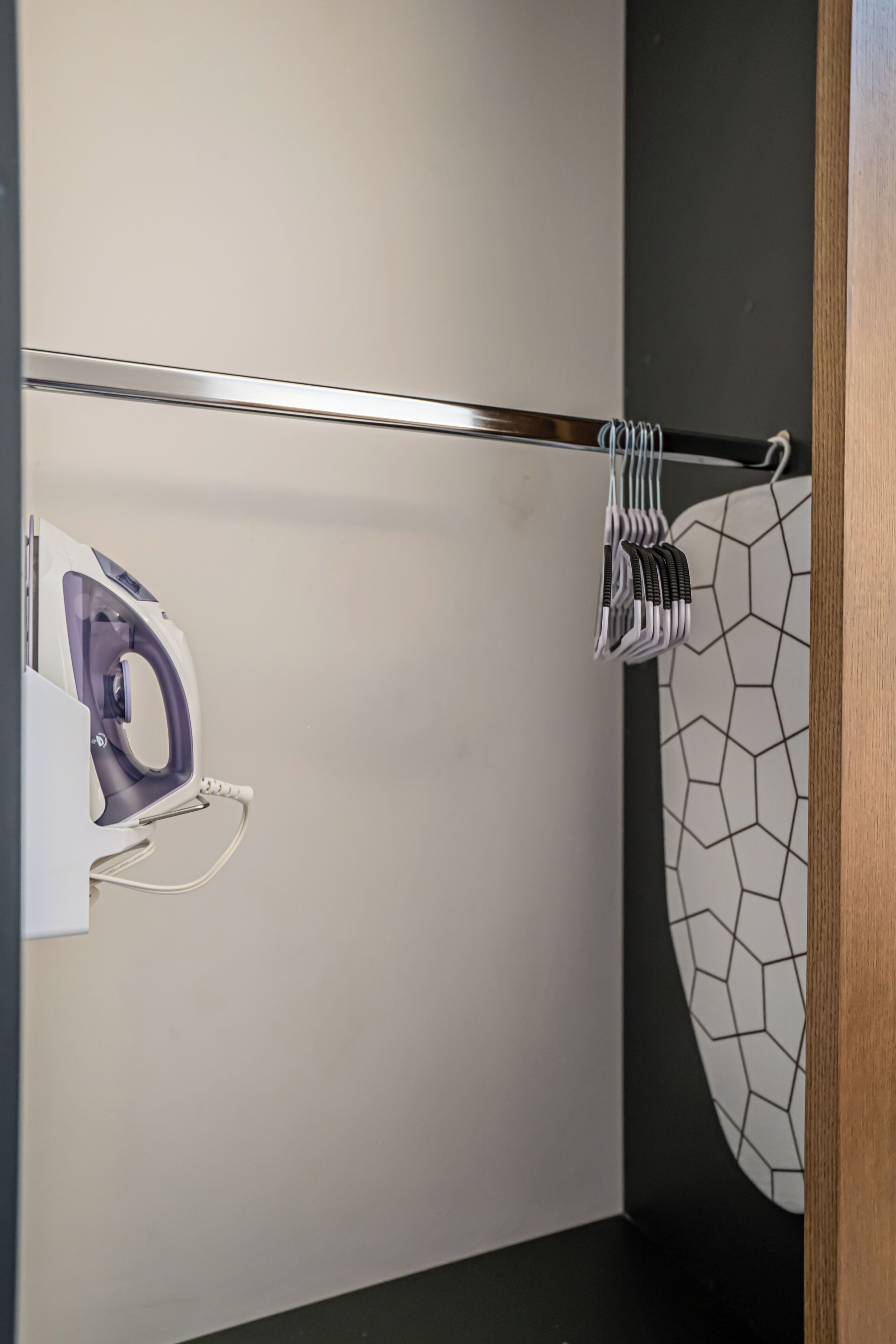 A bathroom with a towel rack, an iron, and a towel with a geometric pattern.
