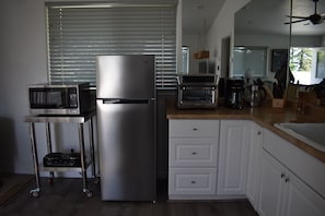 Eine Küche mit einem Edelstahlkühlschrank, einer Mikrowelle, einem Toaster und einer Kaffeemaschine.