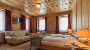Ein Zimmer in einer Holzhütte mit einer Couch, einem Bett, einem Fernseher und einer Lampe.