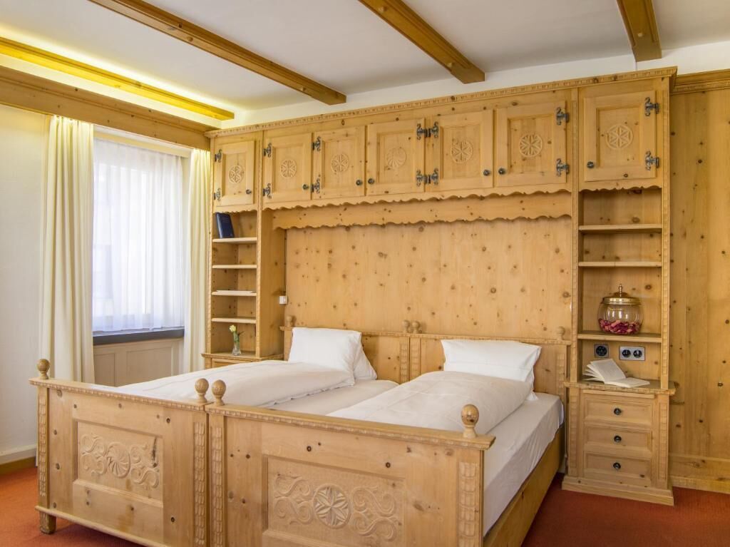 Una cama doble de madera con cabecera, una mesita de noche con lámpara y un mueble de estanterías empotrado con espacio de almacenamiento.