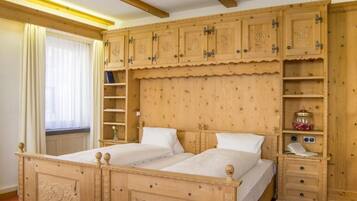 Una cama doble de madera con cabecera, una mesita de noche con lámpara y un mueble de estanterías empotrado con espacio de almacenamiento.