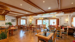 Eine großzügige Hotelhalle mit Holzböden, mehreren Esszimmertischen und einer gemütlichen Sitzecke.