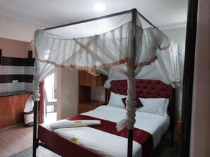 Een hotelkamer met een hemelbed, een rode hoofdbord en een witte baldakijn.