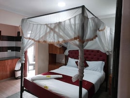 Una habitación de hotel con una cama con dosel, un cabecero rojo y un dosel blanco.