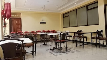 Un comedor con mesas y sillas, una puerta de madera y un ventanal grande.