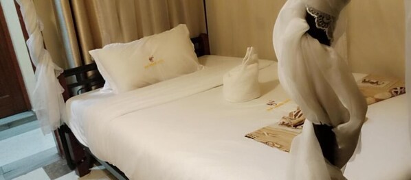Une chambre d’hôtel avec un lit, des oreillers, une serviette et un objet décoratif posé sur le lit.