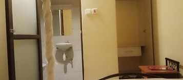 Un baño con lavamanos blanco, un espejo y un perchero para toallas.