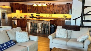 Un salon moderne avec une table basse en bois, deux canapés et une cuisine en arrière-plan.