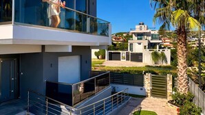 Una moderna casa a due piani con un balcone, un prato curato e una palma.