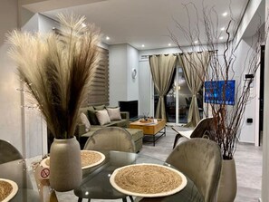 A modern living room with a sofa, coffee table, and dining area with chairs and a vase of pampas grass. - Allure Villa, beachfront, featuring a gym, sauna, and jacuzzi (Porto Rafti)