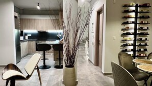 Un interno moderno con un'area pranzo con sedie contemporanee e un vaso centrale con rami. Si intravede in secondo piano una cucina con un piano di lavoro scuro e un tavolo da pranzo.