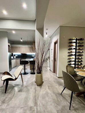 A modern interior with a dining area, a kitchen, and a wine rack. - Allure Villa, beachfront, featuring a gym, sauna, and jacuzzi (Porto Rafti)