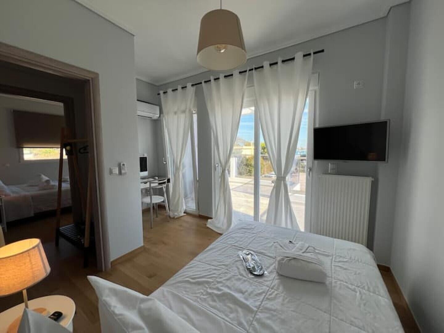 A hotel room with a bed, a desk, a chair, a TV, and a window with curtains.