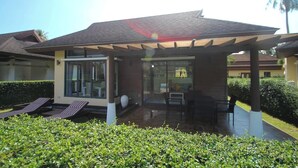 Ein modernes Haus mit einer überdachten Terrasse, einer Glastür und einem Poolbereich.