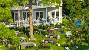 A well-maintained outdoor area with a dining setup, a large tree, and a building with a sign reading 'Craft Beer.' - 30A - Hidden Lakes Condo Rentals (Santa Rosa Beach)