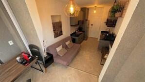 A compact living space with a kitchenette, a sofa, a dining area, and a hanging light fixture. - Cozy studio near Paulista Avenue (São Paulo)