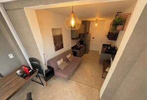 A compact living space with a kitchenette, a sofa, a dining area, and a hanging light fixture. - Cozy studio near Paulista Avenue (São Paulo)