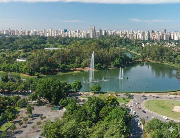 Vista aerea di un parco con una fontana, circondato da alberi e sullo sfondo la linea dell'orizzonte cittadino.