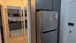 A modern kitchen with a stainless steel refrigerator, a microwave, and a sink. - Cozy studio near Paulista Avenue (São Paulo)