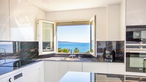 Eine moderne Küche mit einem großen Fenster, einer Kaffeemaschine und einer Waschmaschine.