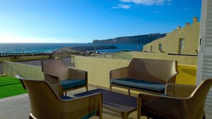 Eine Terrasse mit Korbmöbeln und Meerblick.