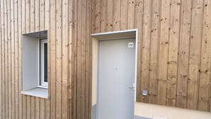 Pared exterior de madera con una puerta marcada con el número 22 y una ventana.