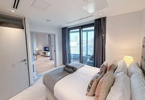 Ein modernes Hotelzimmer mit einem großen Bett, einem Fernseher und einem Balkon mit Blick auf die Stadt.