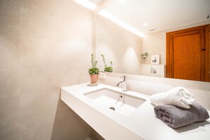 Ein modernes Badezimmer mit einem weißen Waschbecken, einem Spiegel und einer Holztür.