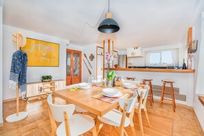 Eine moderne Küche mit Holzausbau, einem Esstisch für vier Personen und einem großen Fenster.