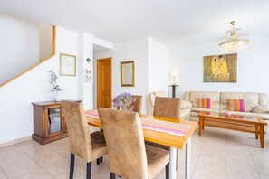 A dining area with a wooden table and chairs, a sofa, a coffee table, and a chandelier. - Nice duplex with sea views & terrace in Alcalá (Guía de Isora)