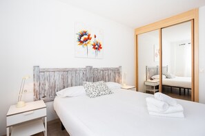 Une chambre à coucher avec un lit, une table de chevet, un miroir et un tableau accroché au mur.