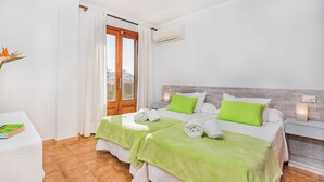 Quarto de hotel com duas camas, uma porta de madeira, unidade de ar condicionado e vista para a cidade.